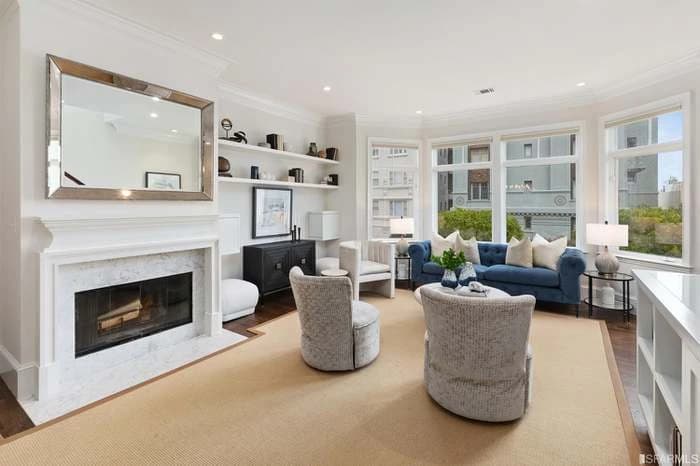 Living room at 1911-B Vallejo Street with bay windows, blue seating, and a marble fireplace